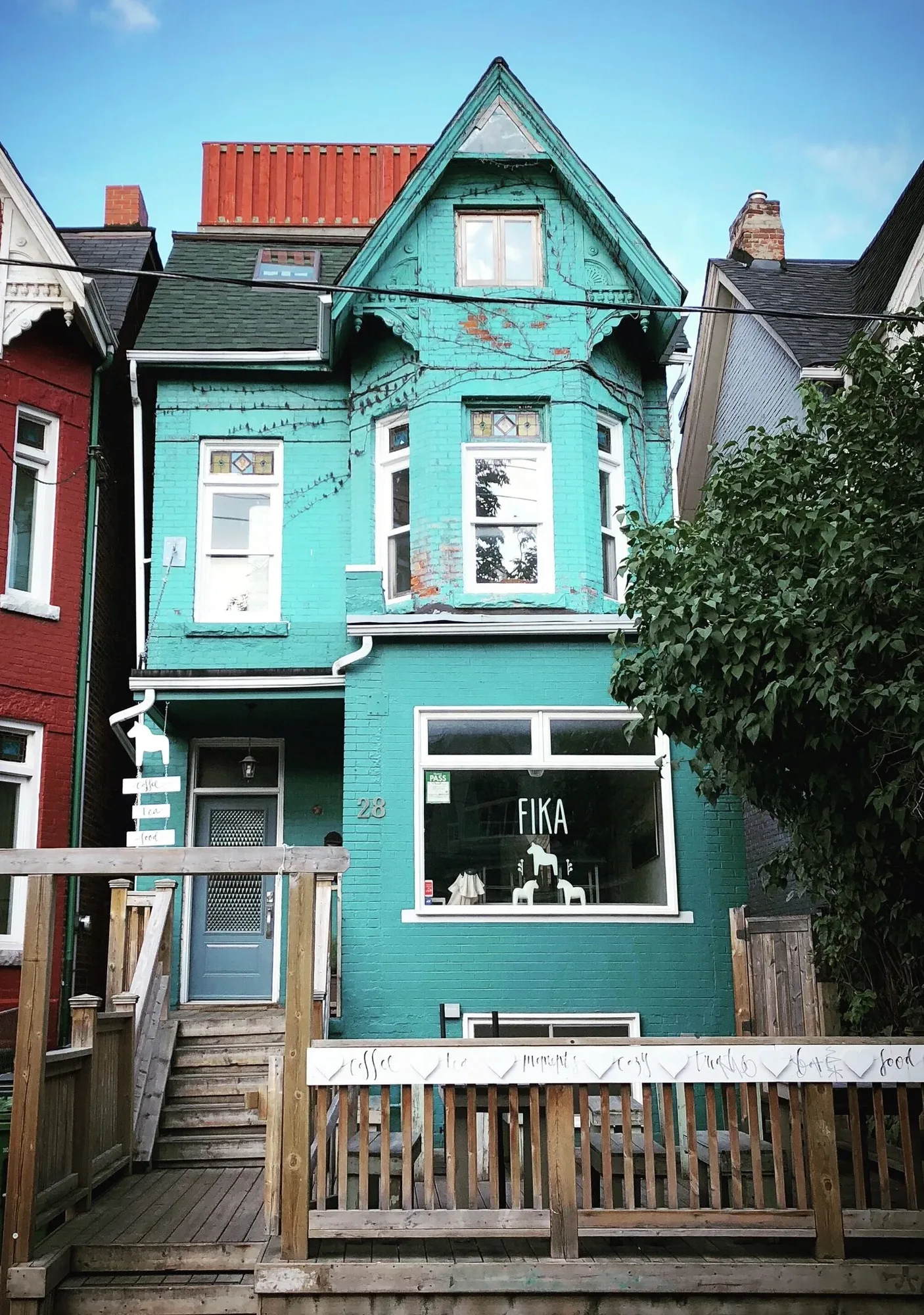 Charming rustic exterior of FIKA Cafe with blue front and Dala horse mascot
